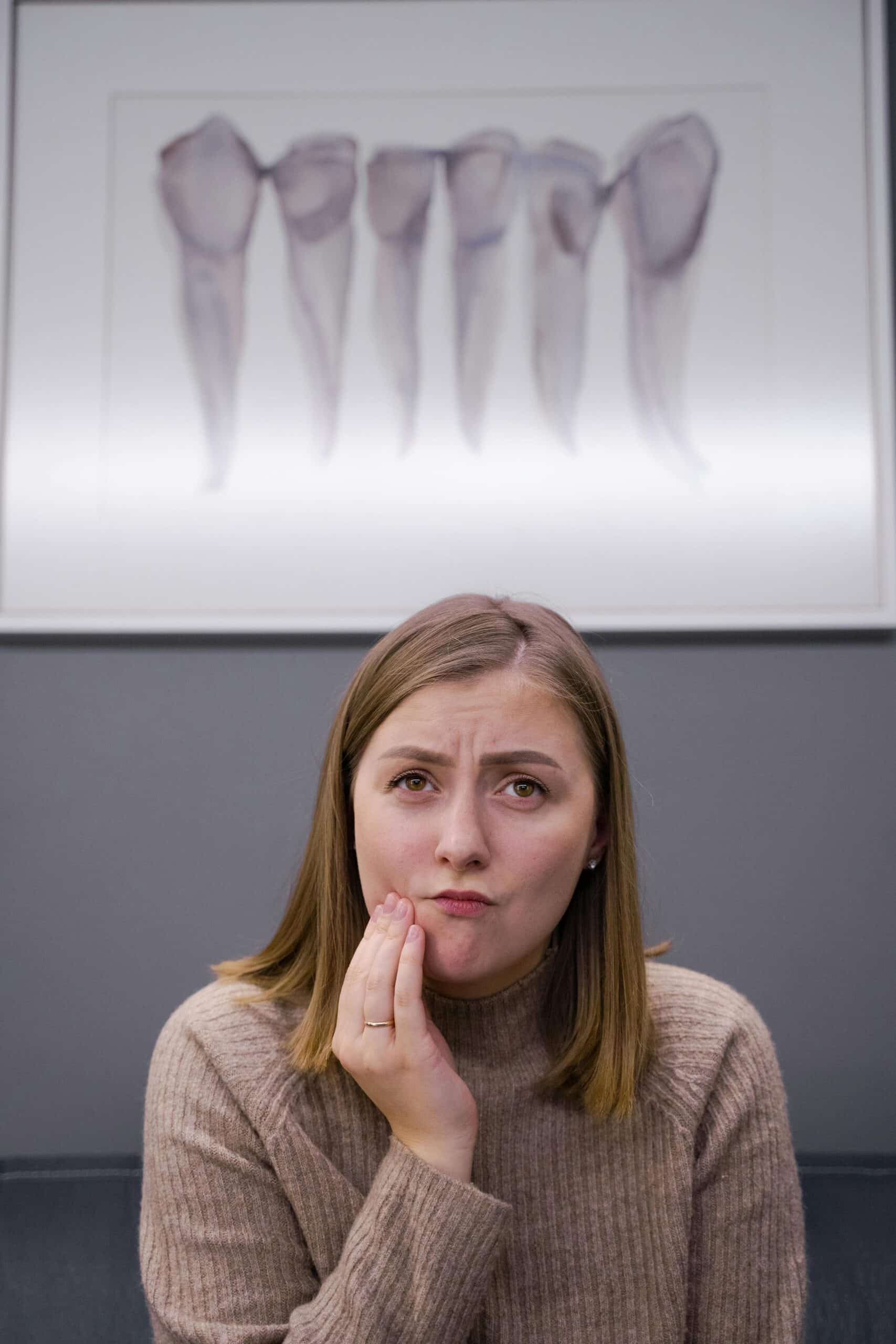 Caucasian woman feels toothache in modern dental clinic. Concerned expression.